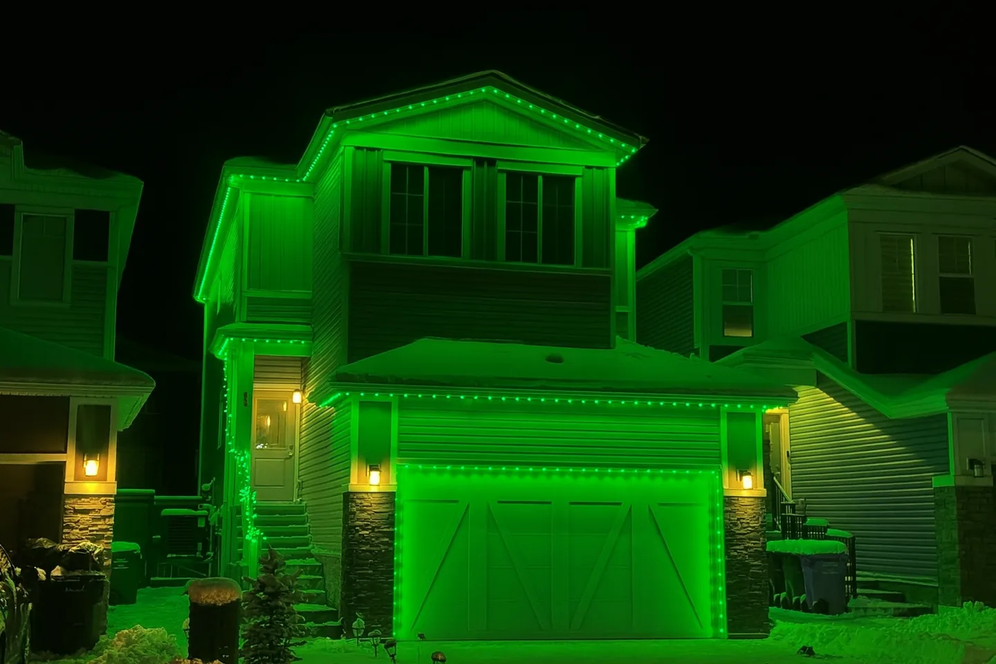 Kelowna home illuminated with green permanent Christmas lights along the roofline and garage