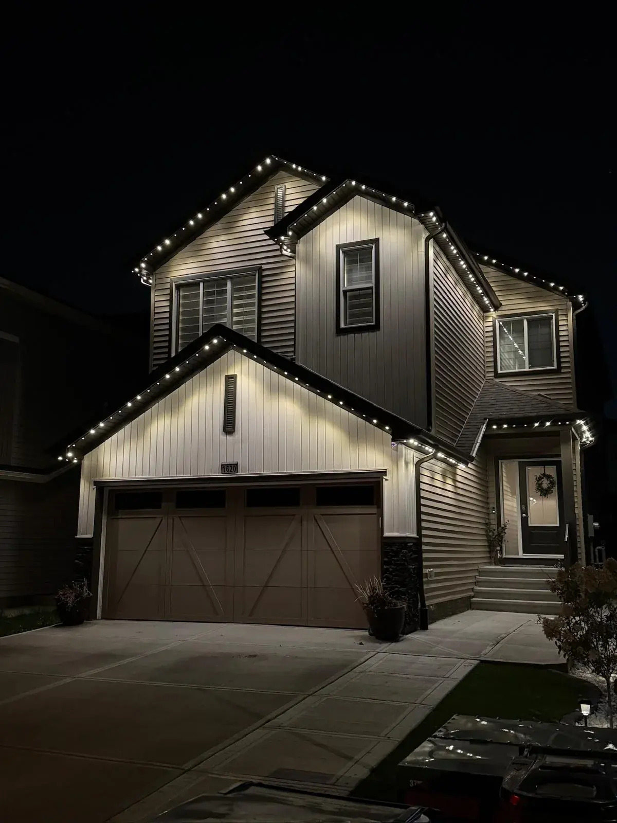 Warm-white permanent Christmas lights on an Edmonton home at night