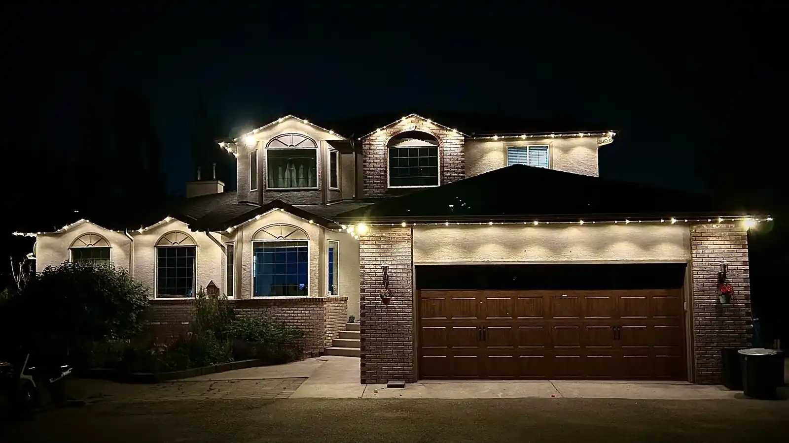 Warm white permanent outdoor lights on a Kelowna home at night