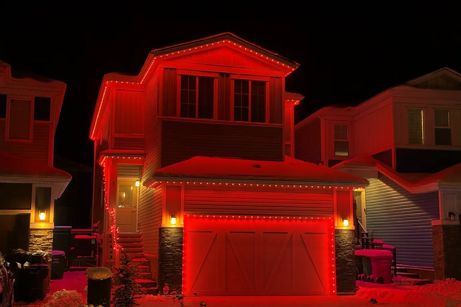Red permanent outdoor lights on a Kelowna home at night
