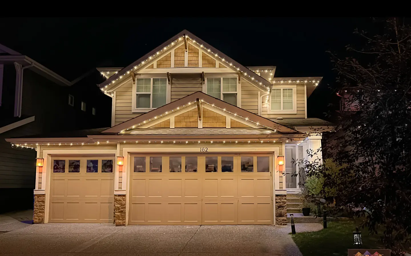 Warm white permanent Christmas lights outlining an Edmonton home at night