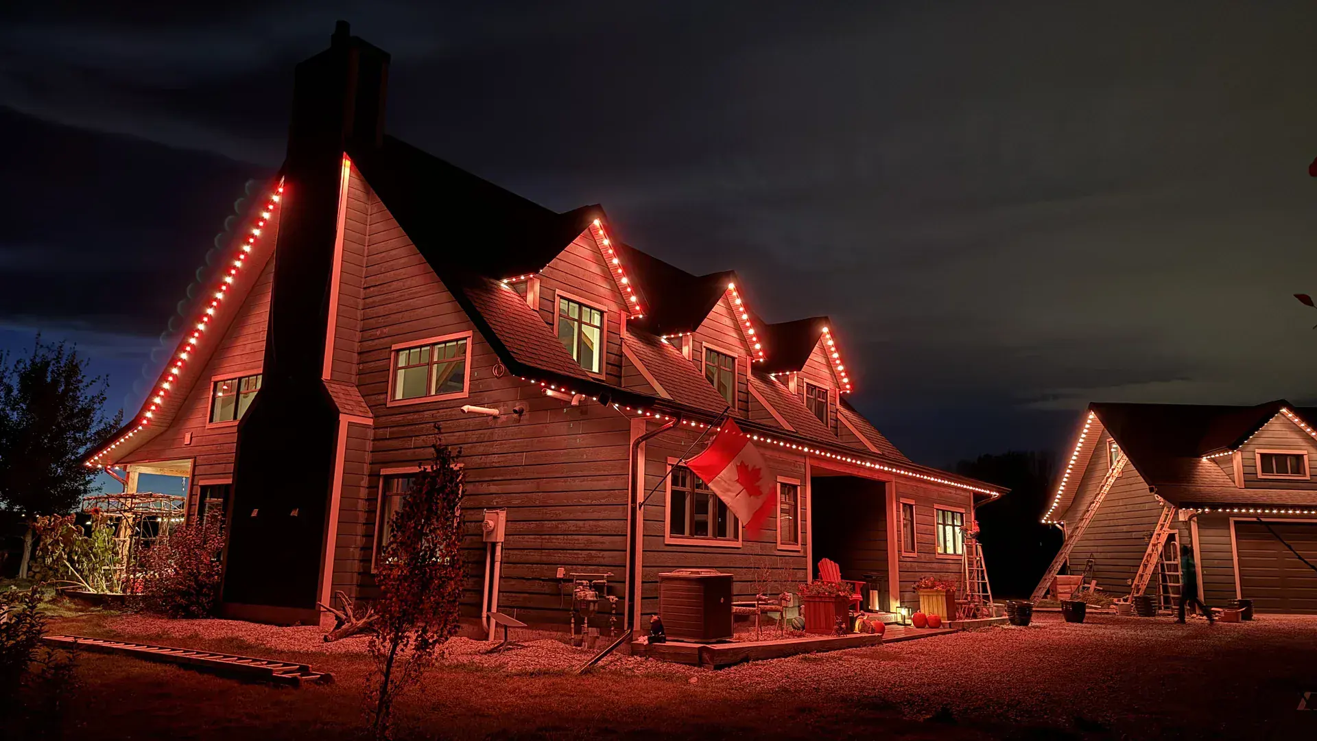 Full-perimeter permanent lighting illuminating the front and rear rooflines of the same home