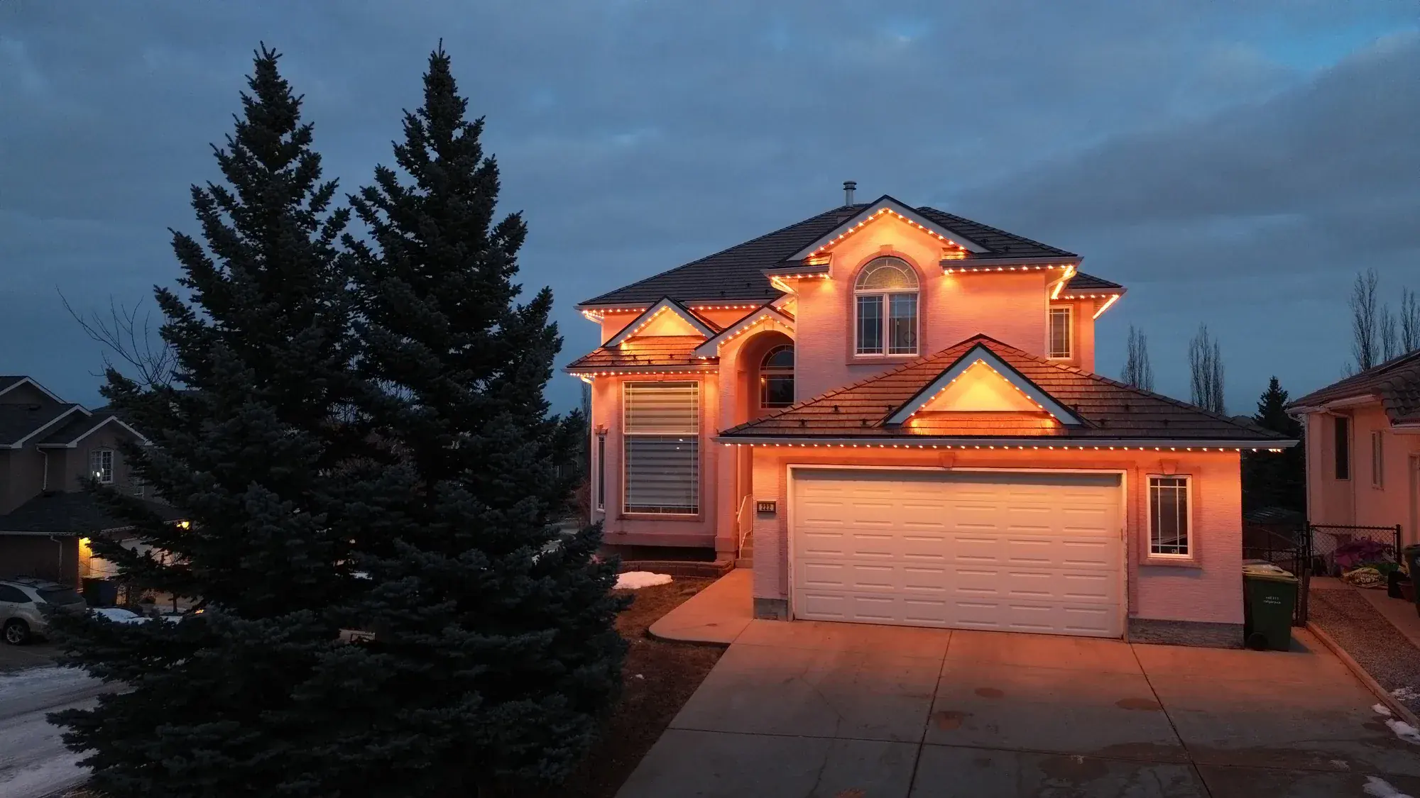 Larger Edmonton home with warm-white permanent lights along multiple roofline peaks